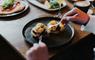A man eats poached eggs on sourdough with avocado at hs1 cafe bar in the Royal Hotel.